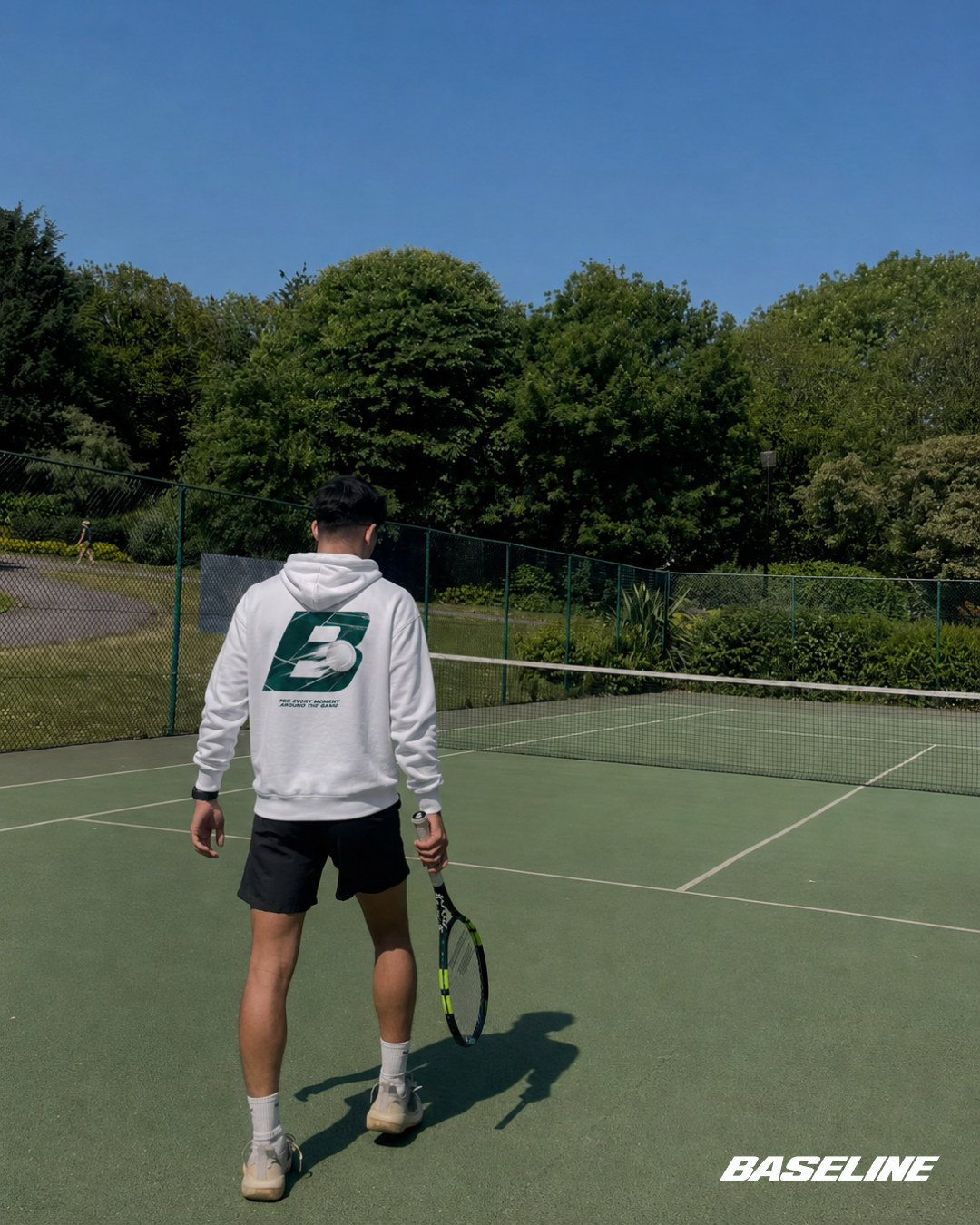 Baseline Court Green hoodie worn on a tennis court
